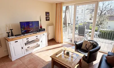 geräumiger Wohnraum mit Couch, Sesseln und Sideboard