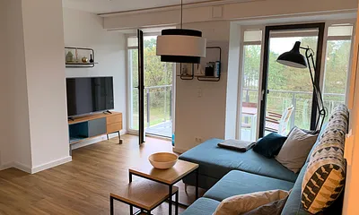 offener Wohnbereich mit Couch, Couchtisch, Stehlampe, Sideboard, Smart-TV mit Netflix Zugang, DVD-Player und Musikanlage
