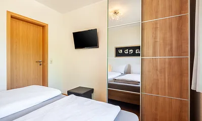 Komfortables Schlafzimmer mit Doppelbett, Fernseher und großzügigem Kleiderschrank