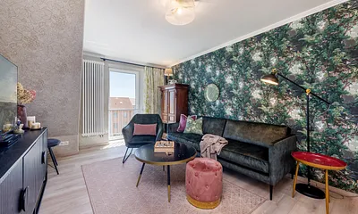 Das schöne Wohnzimmer mit samtigen Sitzmöbel, Mustertapeten und ausgewählten Antiquitäten.