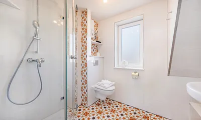 Das Bad mit einem Stück Dachschräge, schönen Vintagefliesen ...