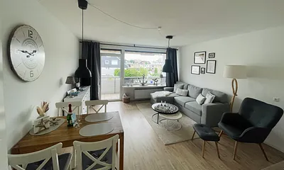 Wohnzimmer mit Schlafcouch und Esstisch mit Balkonaussicht