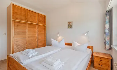 Schlafzimmer mit Doppelbett und dreitürigen Kleiderschrank