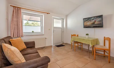 Wohnbereich mit Couch und Esstisch und TV