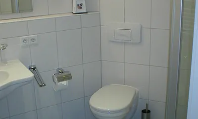 Ein maritim gestaltetes Bad mit Dusche und Fußbodenheizung gehört zum Appartment. 