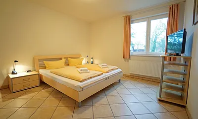 Schlafzimmer mit Doppelbett und Fernseher