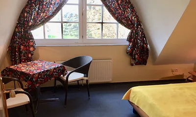 Geräumiges Schlafzimmer mit kleiner Sitzgruppe und Holz-Kinderbett (1,20 mal 0,60 m)
