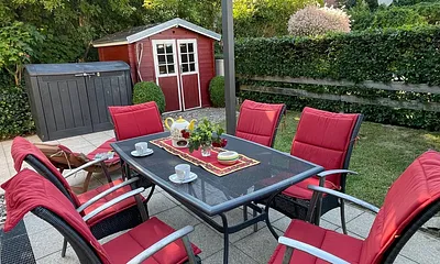 Sonnenterrasse im umzäunten Garten und Gartenhaus für Sonnenliegen und Fahrräder