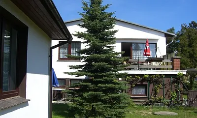 Ferienhaus  (Fenster Wohnzimmer mit Blick in den Garten), im Hintergrund Wohnhaus der Vermieter 