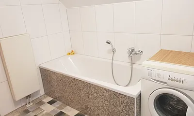 Eine Badewanne lädt zum Relaxen ein, das Luxusbadezimmer verfügt über einen modernen Natursteinboden