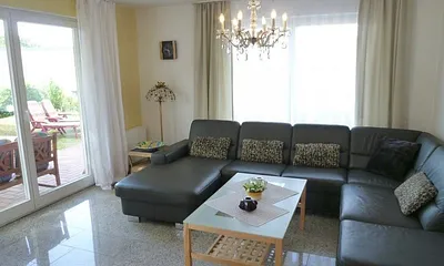 Großzügiges, helles Wohnzimmer mit drei großen Terrassentüren, exklusiver Natursteinboden in der gesamten Wohnung