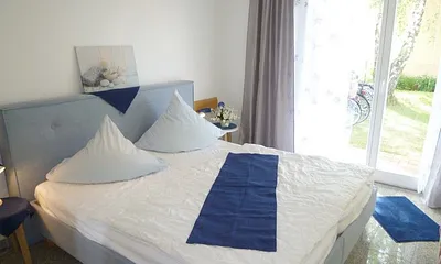 Modernes Schlafzimmer mit chicem blauen Bett, doppelflüglige Tür zur Terrasse