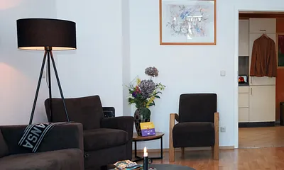 Sie stehen gerade im Flur und blicken durch die Küche in das Wohnzimmer.... Links geht es in das Bad, wo sich auch der Trockner und die Waschmaschine befindet.