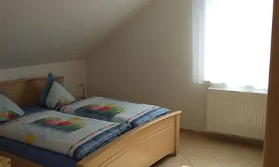 Helles Schlafzimmer mit Doppelbett, großem Kleiderschrank und ausreichend Platz für ein Kinderbett