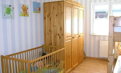 Kinderzimmer mit Etagenbett sowie Kinderbett und Hochstuhl