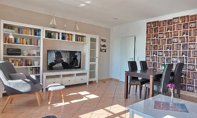 Wohnzimmer mit Esstisch, Sessel, und TV