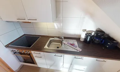 Küchenzeile mit Geschirrspüler, Herd mit Ceranfeld, Wasserkocher und Toaster.