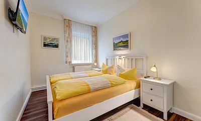 Schlafzimmer mit Doppelbett, Flat-TV, Jalousie vor dem Fenster