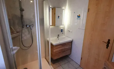 Badzimmer mit Dusche, Waschbecken und Toilette.