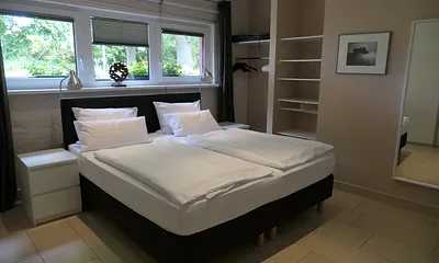 Schlafzimmer mit Hotelboxspringbett (1,80 x 2 m, Bandscheibenfederkernmatratze), integrierter offener Kleiderschrank, Kommode