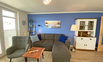 Wohnzimmer mit einem 2-Sitzer, Sessel, Vitrine, TV-Board, mit Smart TV und Ministereoanlage