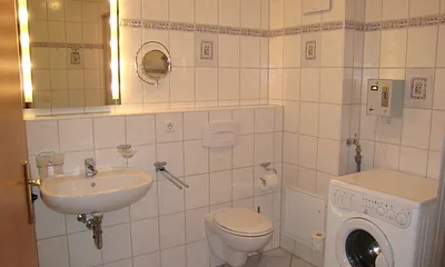 Blick ins großzügige Bad mit Münzwaschmaschine, Fön und Kosmetikspiegel.