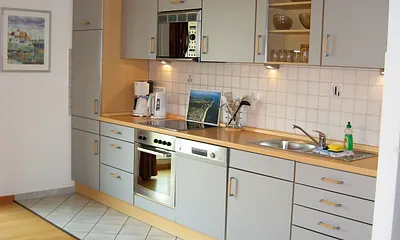 Blick auf den gut ausgestatteten Küchenbereich mit vielen E-Geräten, Geschirrspüler und Backofen.