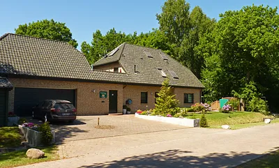 Haus am Wald - Frontansicht mit Parkbereich und Fahrrad-Abstellraum am linken Bildrand