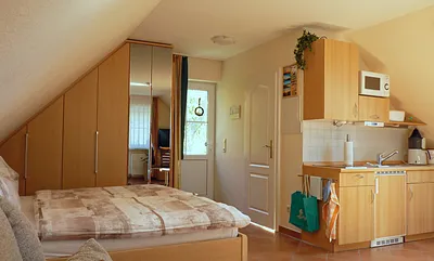 Haupt- und Badeingang (rechts) mit Blick vom Wohn-/Schlafbereich, ausgestattet mit Doppelbett inkl. beids. Nacht- und Einbauschranken, vollst. gefliest mit Fußboden- und Wandheizung