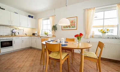 Esstisch un im Hintergrund die komplett eingerichtete Küchenzeile