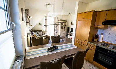 Esstisch mit Küchenzeile und Wohnraum im Hintergrund