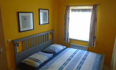 Schlafzimmer mit Doppelbett 180x200 cm, am Fenster befindet sich ein Verduncklungsrollo