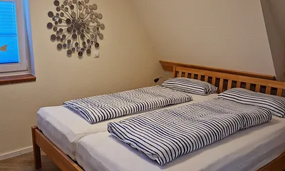 Schlafzimmer 1 im 1. OG mit Doppelbett, angrenzendem Duschbad und TV