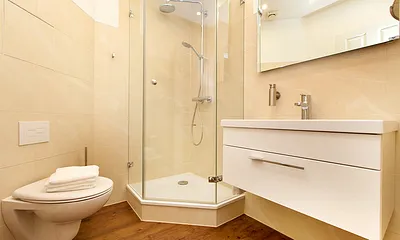 Das schicke Bad mit großem Waschtisch, Echtglasdusche und Regenbrause sowie WC und Fön.