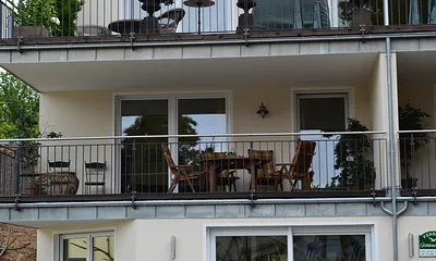 Detailansicht des großen Balkones mit Tisch und Stühlen zum Erholen.