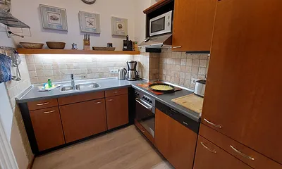 Die separate Küche besticht durch eine komfortable Ausstattung mit Induktionskochfeld, Backofen, Geschirrspüler und Kühlschrank mit Gefrierfach