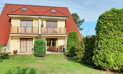 Blick auf die mit Holzmöbeln ausgestattete Sonnenterrasse der Fewo "Gartentraum" mit Glasdach- unten rechts - ,sowie  wunderschönem Rasengarten