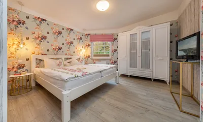 Schlafzimmer mit TV.  Das Doppelbett ist bequeme 1,80x2m breit. Plissee und Raffrollo am Fenster haben Verdunkelungsfunktion.