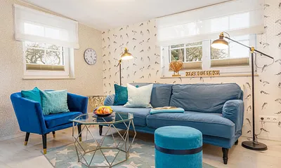 Die Fenster im Wohnzimmer sind mit Raffgardinen und Verdunkelungsplisses bestückt.