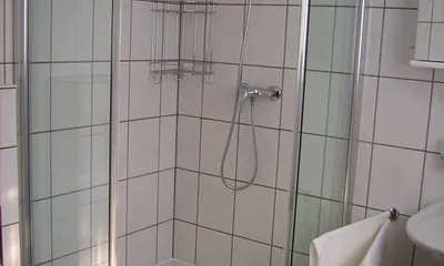 Im Badezimmer befindet sich ein WC, eine Dusche und ein Waschbecken. Das Bad hat ein eigenes Fenster.