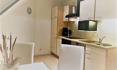 Blick in die moderne Küche im cremeweißen Ton mit Essecke