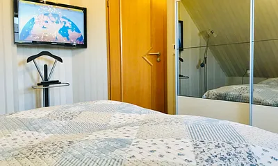 Schlafzimmer mit Doppelbett, Fernseher und Schrank