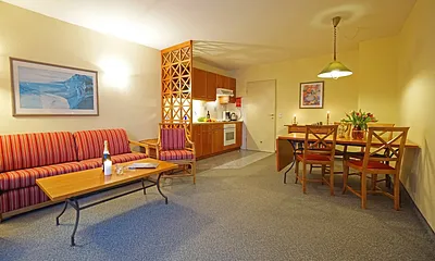 Wohnzimmer mit Schlafcouch, Esstisch und Küchenzeile