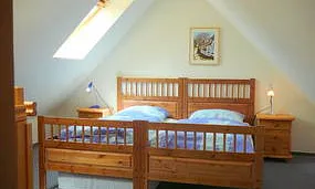 Oberes Schlafzimmer mit einem Doppel- und einem Einzelbett. Die Fenster sind mit Rollos zur Abdunkelung ausgestattet.