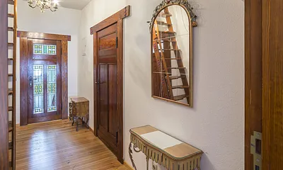 Flur mit Eingangstür. Hinter der Dekotreppe kommt man durch den begehbaren Kleiderschrank ins Bad 