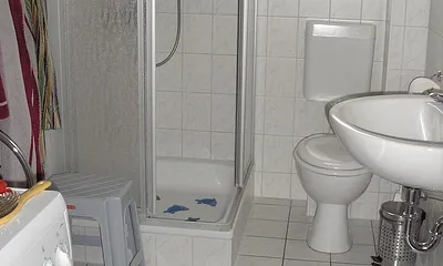 Badezimmer mit Dusche und Münzwaschmaschine