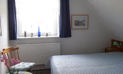 blaues Schlafzimmer mit kleiner Sitzgelegenheit