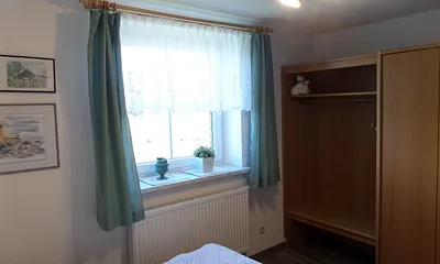 grünes Schlafzimmer mit Schrank und hellem Fenster