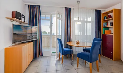 Wohnzimmer mit Flachbild-TV, Blick auf Esstisch und Balkon