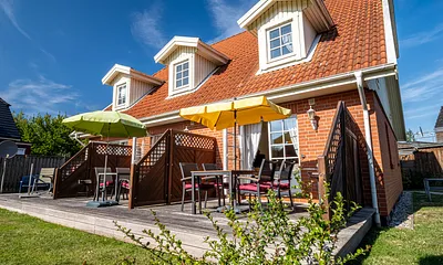 Ferienhaus Residenz zu den 3 Tannen Zingst - Aussenansicht rechter Reihenendhausteil mit Terrasse, Gartenmöbeln, großer Wiese und einer Schaukel für die kleinen Gäste